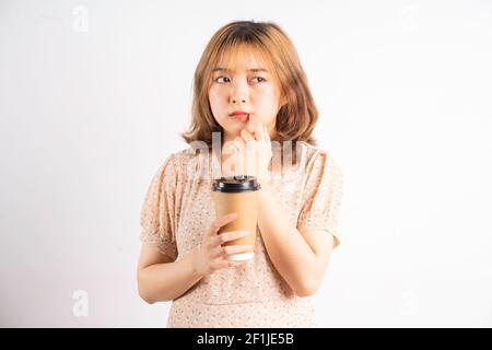 Junge asiatische Mädchen hält Kaffeetasse mit Ausdruck auf dem Hintergrund Stockfoto