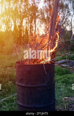 Müllverbrennung im rostigen Metallfass. Brennende Äste und altes Gras vom Grundstück. Frühjahrsputz von Garten und Garten. Eine sichere alte Stockfoto