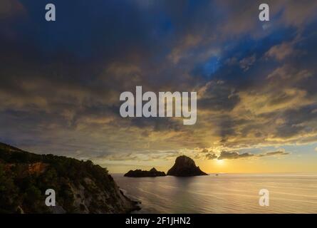 Insel Es Vedra in den Gewässern von Ibiza, weltweit bekannt als einer der magischsten Orte. Unglaublicher Sonnenuntergang mit Wolken. Stockfoto