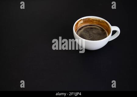 Weiße Tasse aromatischen frisch gemahlenen arabica-Kaffee auf schwarzem Hintergrund. Die Tasse befindet sich auf der Untertasse. Weiße Tasse aromatisch frisch gemahlener arabica-Coff Stockfoto