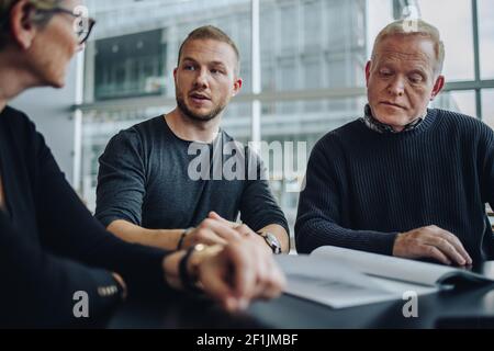 Geschäftsleute diskutieren während der Besprechung ein Vertragsdokument. Geschäftsleute diskutieren Pläne in einem Meeting in einem modernen Sitzungssaal. Stockfoto