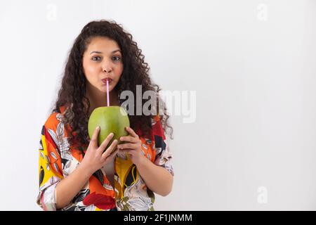 EIN LOCKIGER TEENAGER TRINKT GERNE KOKOSWASSER Stockfoto