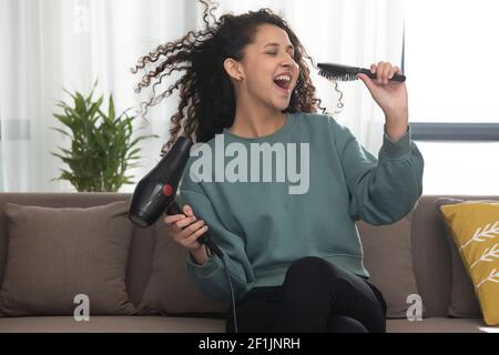 EIN LOCKIGER TEENAGER, DER ALLEINE SITZT UND DEN GESANG IMITIERT Stockfoto