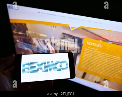 Person, die Handy mit Logo von Bangladesh Export Import Company Limited (BEXIMCO) auf dem Bildschirm vor der Webseite hält. Konzentrieren Sie sich auf die Telefonanzeige. Stockfoto