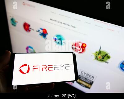 High-Angle-Ansicht der Person hält Handy mit Logo der US-Cyber-Unternehmen FireEye Inc. Auf dem Bildschirm vor der Webseite. Konzentrieren Sie sich auf die Telefonanzeige. Stockfoto