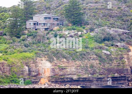 Felsenerosion unter einem Haus in Sydney auf der Landzunge am Avalon Beach in Sydney, NSW, Australien, Küstenerosion und Klimawandel Stockfoto