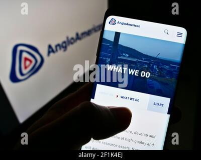 Person, die Mobiltelefon mit Website des globalen Metall- und Bergbauunternehmens Anglo American plc auf dem Bildschirm mit Logo hält. Fokus auf der Mitte des Telefondisplays. Stockfoto