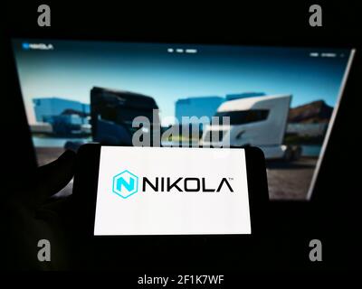 Person, die Smartphone mit dem Logo der US-Firma Nikola Corporation für emissionsfreie Fahrzeuge auf dem Bildschirm vor der Webseite hält. Konzentrieren Sie sich auf die Telefonanzeige. Stockfoto