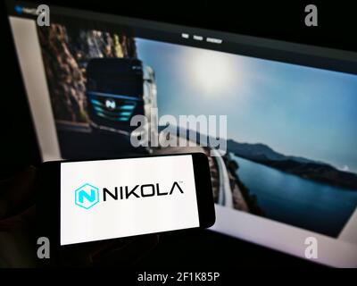 Person mit Mobiltelefon und Firmenlogo des US-LKW-Herstellers Nikola Corporation auf dem Bildschirm vor der Webseite. Fokus auf Handy-Display. Stockfoto