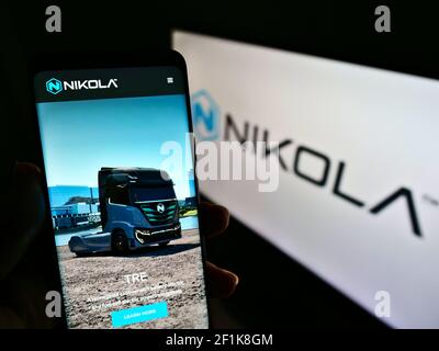 Person, die Mobiltelefon mit der Webseite des US-amerikanischen Elektrofahrzeugunternehmens Nikola Corp. Auf dem Bildschirm vor dem Logo hält. Fokus auf der Mitte des Telefondisplays. Stockfoto