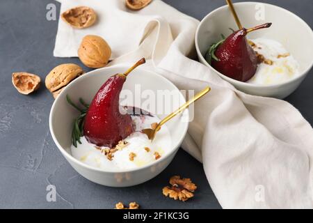 Schüsseln mit süßen pochierten Birnen in Rotwein und Eis Auf dunklem Hintergrund Stockfoto