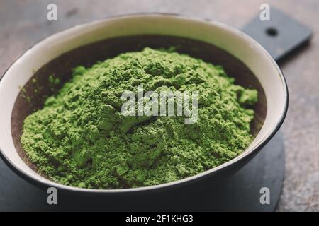 Schüssel mit gepuderter Matcha-Tee auf grunge Hintergrund, Nahaufnahme Stockfoto