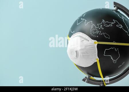 Globus mit Atemschutzmaske auf farbigem Hintergrund Stockfoto