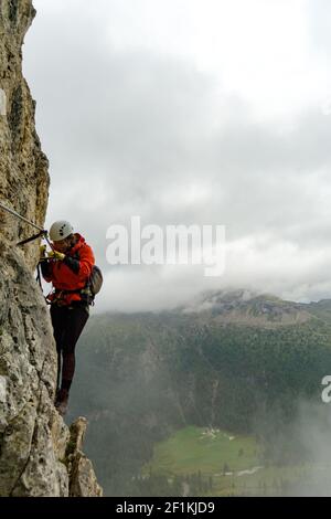 Attraktive junge Bergsteigerin auf einem Klettersteig in Die Dolomiten Stockfoto