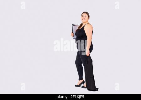 In voller Länge große Körpergröße Foto von niedlichen Business-Dame, hält Zwischenablage Dokumente Papiere. Bereit für Konferenzen. High-Heels-Specs, formeller Tragekomfort Stockfoto