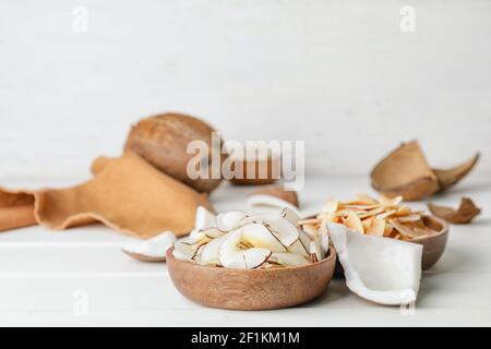 Schalen mit leckeren Kokosnussspäne auf hellem Holzhintergrund Stockfoto