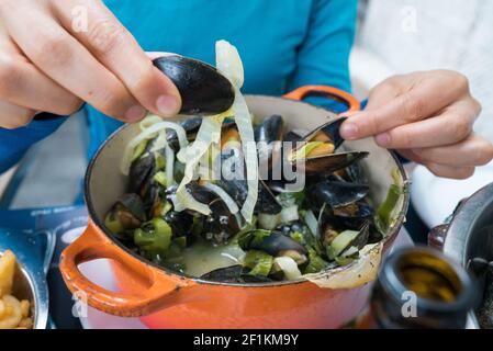 Hände einer Frau, die traditionelle Muscheln und pommes frites isst Gericht genannt Moules et Frites Stockfoto