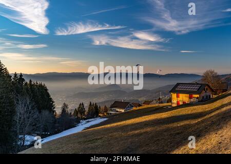 Paragleiter schweben von Furx im Abendrot ins Rheintal hinter. Gleitschirme schweben von Furx in das Rheintal bei Sonnenuntergang. Kummenberg Stockfoto