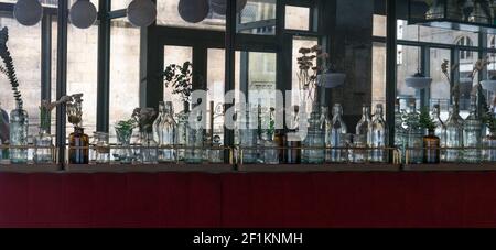 Dekorative Glasflaschen säumen die Wand in einem gemütlichen kleinen Restaurant in Rennes mit verspiegelten Wänden und Stockfoto