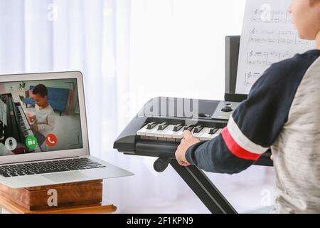 Kleiner Junge studiert Musik mit seinem Freund online zu Hause Stockfoto