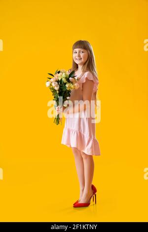 Nettes kleines Mädchen mit Mutter Schuhe und Strauß von schön Blumen auf farbigem Hintergrund Stockfoto