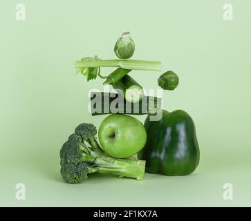 Frisches grünes Gemüse und Obst auf grünem Hintergrund. Gleichgewicht schwimmende Lebensmittelbalance. Stockfoto