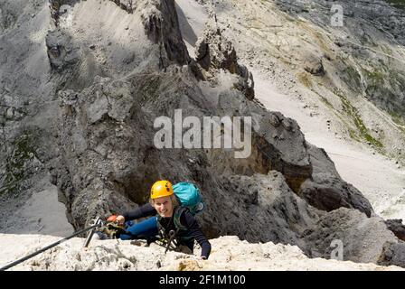 Attraktive blonde Klettererin auf einem steilen Klettersteig in Die italienischen Dolomiten Stockfoto