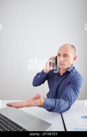 Reife Geschäftsmann lesen Artikel oder Bericht auf Tablet-Computer, wenn Telefonische Gespräche mit Kollegen oder Mitarbeitern Stockfoto