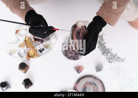 Künstlerische Untersetzer. Eine junge Frau schafft Untersetzer aus Harz. Geschenkverpackung.Design-Element für ein Geschenk. Erstellung. Blick von oben. Künstlerischer Hintergrund. Stockfoto