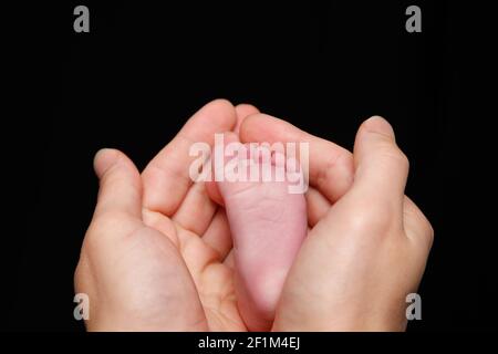 Neugeborenes Baby Füße in die Hand des Vaters Stockfoto