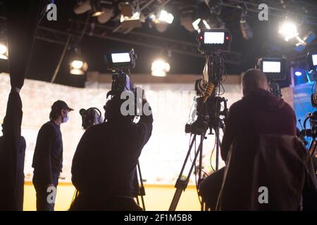 Maskierter Kameramann dreht eine Fernsehshow im Studio. TV Stockfoto