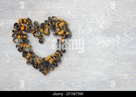 Herzform von Baumrinde Peelings auf weiß lackiertem Holz. Kirschbaumrinde aus gefälltem Baum geschält. Natürlich geformte Spiralen und Whorlen. Stockfoto