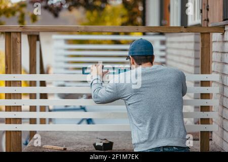 Zimmermann mit Wasserwaage auf der Geländer der Terrasse Stockfoto