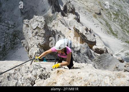 Attraktive Brünette weibliche Kletterin auf einem steilen und exponierten Via Klettersteig in den Dolomiten Stockfoto