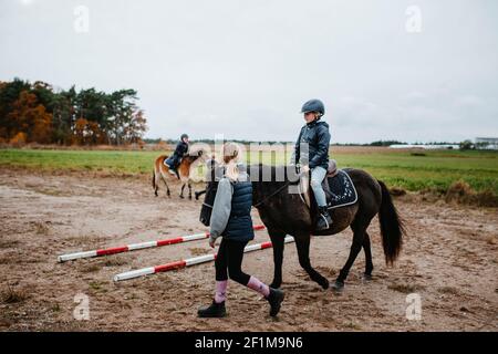 Mädchen reiten Pony auf Paddock Stockfoto