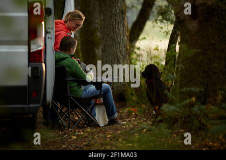 Pärchen genießen Kaffeepause in der Nähe des Autos Stockfoto