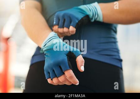 Professionelle Radfahrerin, die beim Training Handschuhe anziehen. Sport, extreme und aktive Lifestyle-Konzept Stockfoto