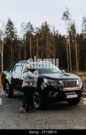 Ein Paar umarmt sich vor dem Auto Stockfoto