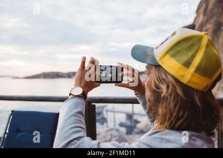 Mann auf See, der mit dem Handy fotografiert Stockfoto