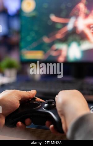 Nahaufnahme von konkurrierenden Spieler halten Joystick spielen Weltraum-Shooter-Videospiele an leistungsstarken Computer spät in der Nacht. Professioneller Gamer mit Controller für Online-Meisterschaft sitzen auf Spielstuhl Stockfoto