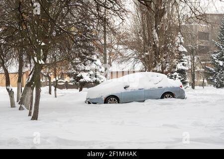 Stadtstraße nach Schneesturm. Autos unter Schnee und Eis stecken. Vergrabenes Fahrzeug in Schneewehe auf der Straße. Parkplätze im Winter nach starkem Schneefall Stockfoto