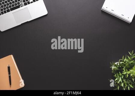 Arbeitsplatz mit Laptop, Bürobedarf. Stilvoller Tischschreibtisch, Bild mit Kopierplatz auf schwarzem Hintergrund Stockfoto