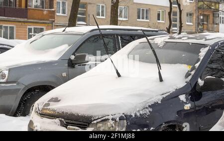 Stadtstraße nach Schneesturm. Autos unter Schnee und Eis stecken. Vergrabenes Fahrzeug in Schneewehe auf der Straße. Parkplätze im Winter nach starkem Schneefall Stockfoto