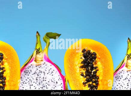 Zwei Hälfte von Papaya und Pitaya mit Grün und Samen auf blauem Hintergrund, Minimalismus Trendy Food, gesunde und detox Essen, Raw Lunch, Copyspace, exotisch Stockfoto