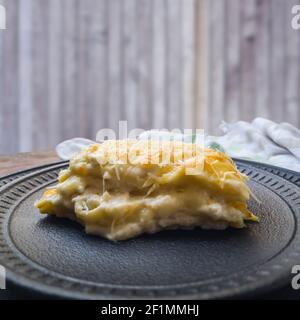 Köstliche Lasagne vier Käse auf schwarzem Keramikplatte mit Holzbrettern Hintergrund. Nahaufnahme, Seitenansicht. Platz für Text kopieren. Stockfoto