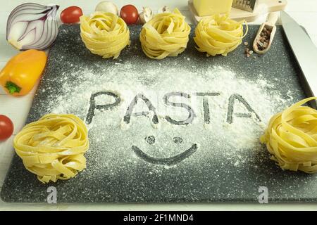 Das Wort Pasta auf einem Pasta-Hintergrund. Pasta Wort auf dem Tisch Zusammensetzung mit Zutaten geschrieben Stockfoto
