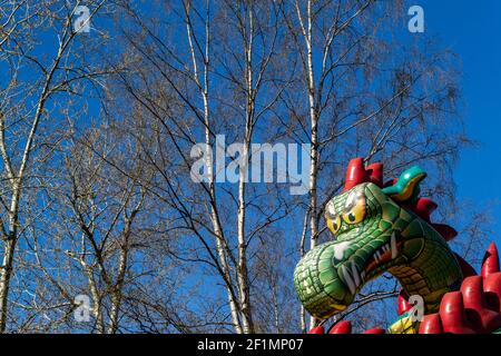 Abstrakter Hintergrund mit dem Kopf eines aufblasbaren Drachen gegenüber Birken und blauer Himmel Stockfoto