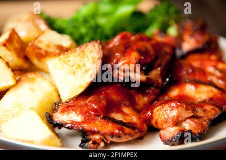 Knusprige Hähnchenschenkel mit fingernden Kartoffeln, Karotten und grünem Gemüse Stockfoto