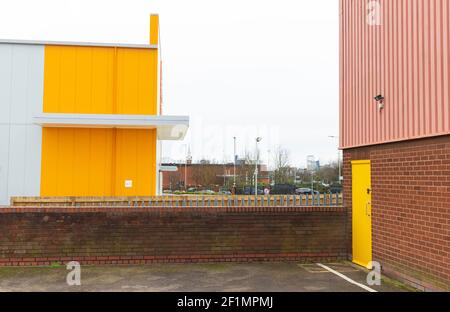 Leuchtend gelbe, rosa gewellte Lagereinheiten, Ziegelwand. Auf dem alten Viehmarkt (Freimens Gemeinsamer Industriepark) zeigt die Zählerhausuhr. Stockfoto