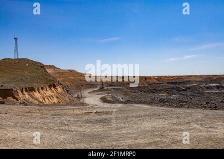 Kupfererz im Tagebau. Panorama des Steinbruchs. Elektrischer Mast und Steinbruchmaschine auf blauem Himmel Hintergrund. Stockfoto